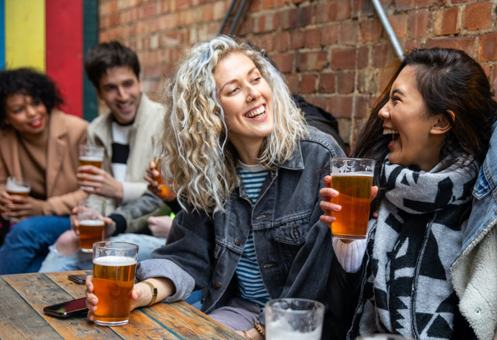 Students laughing and drinking beer outside